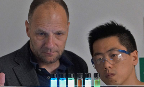Prof. Dr. Uwe Bunz (links) mit Doktorand Jinsong Han mit den fluoreszierenden Substanzen, die die Whiskysorten unterschiedlich leuchten lassen.