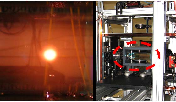 Linkes Bild: Lasergekühlte Metalldampfwolke aus Rubidiumatomen (orange), die im Inneren einer Vakuum-Glaszelle erzeugt wird und eine Temperatur nahe des absoluten Nullpunktes (-273 °C) hat. Im Hintergrund ist ein Teil des Laboraufbaus zu erkennen.  Rechtes Bild: Glaszelle (roter Kreis) mit Spiegeln und Linsen für die Laserstrahlen und Magnetspulen aus Kupferdraht zur Abschirmung vor elektromagnetischen Streufeldern.